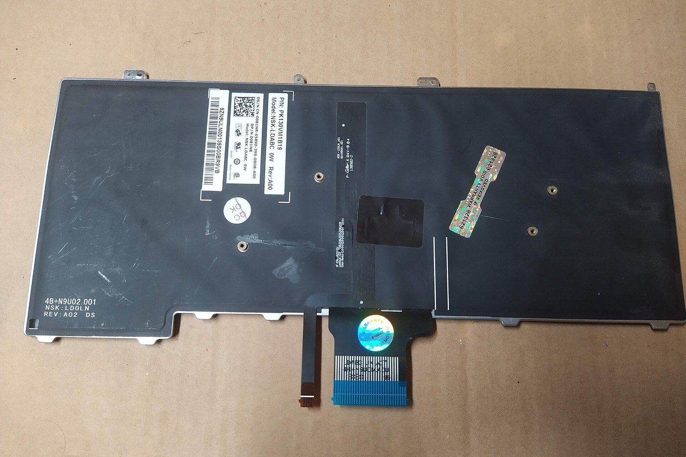 Mặt sau bàn phím laptop đã tháo rời, có cáp dẹt nối vào mainboard