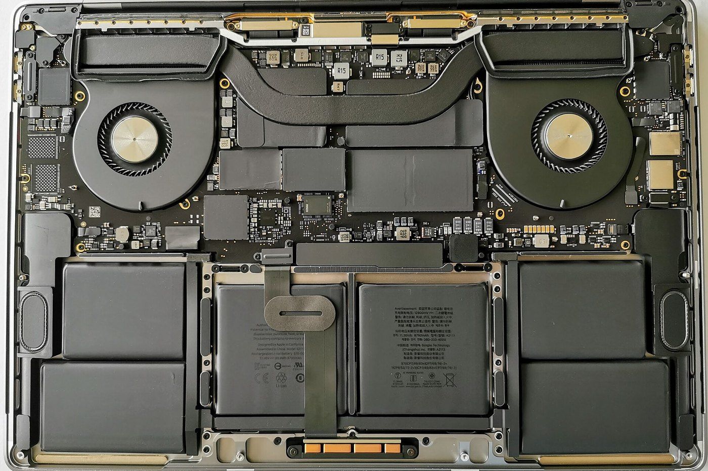 Bên trong Macbook Pro 16 inch khi tháo nắp đáy với hai quạt tản nhiệt, ống dẫn nhiệt, bo mạch và các cell pin