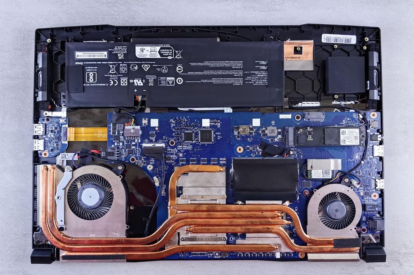 Pin laptop nằm cạnh quạt và bo mạch khi tháo nắp lưng, vị trí kỹ thuật viên thay pin